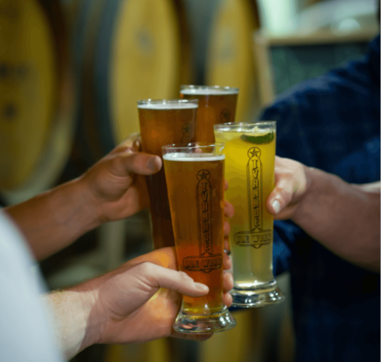 Friends raising glasses of craft beer at Ivanhoe Ale Works in Denison, TX